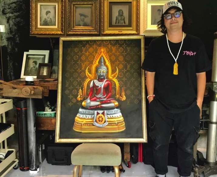 An auction organizer poses next to an âUltraman Buddhaâ painting. From khaosodenglish.com